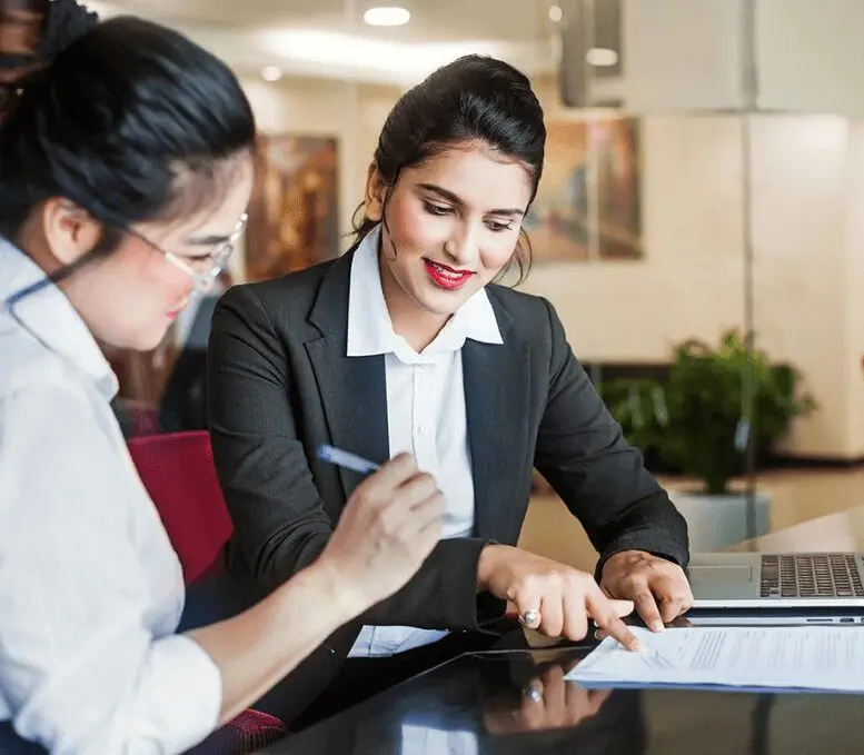 Two women in business attire working on papers.