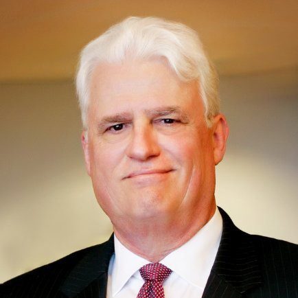 A man with white hair and wearing a suit.