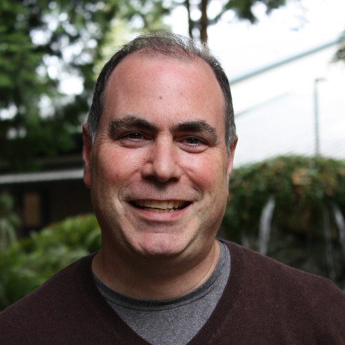 A man with a gray shirt and brown sweater.